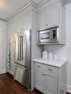 a kitchen with white cabinets and silver appliances