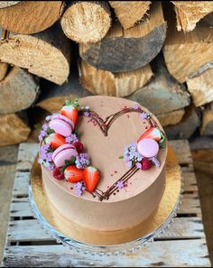 a heart shaped cake sitting on top of a wooden table next to stacked wood logs