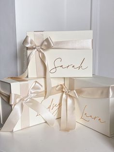 three white boxes with bows and names on them