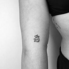 a woman's stomach with a small tattoo on her left arm, and a tiny teddy bear in the middle