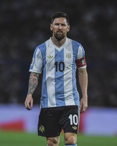 a man with a beard and tattoos on his face is standing in front of a soccer ball