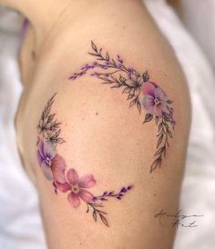 a close up of a woman's shoulder with purple flowers on her left side