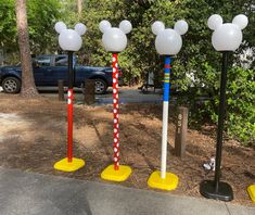 three mickey mouse poles are lined up on the sidewalk