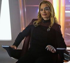 the star trek picard character is sitting in a chair with her hands on her hips