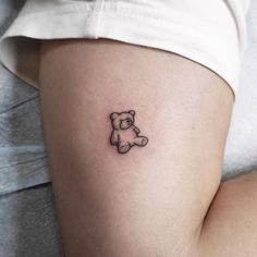 a small teddy bear tattoo on the right side of the thigh, it is black and white