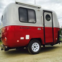 a red and silver trailer parked on top of a dirt field