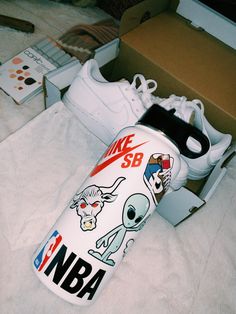 a pair of white sneakers with cartoon stickers on them sitting next to a shoe box