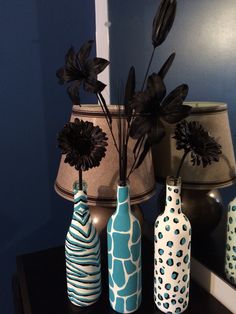 three vases with flowers in them sitting on a table next to a lamp shade