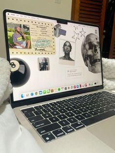 an open laptop computer sitting on top of a white bed next to a stuffed animal