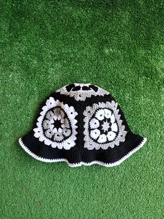 a black and white crocheted hat laying on green grass