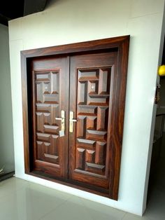 two wooden doors with decorative designs on the side of a wall in an office building