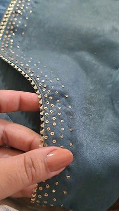 someone is stitching the zippers on a denim jacket with gold rivets