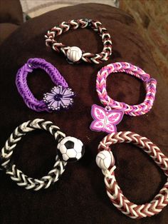 several different colored bracelets with soccer balls on them sitting on a brown cushion in front of a wall