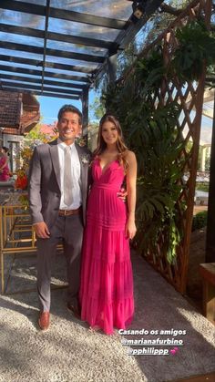 a man and woman standing next to each other in front of a pergola