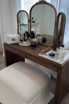 a dressing table with mirror, stool and other personal care items sitting on top of it