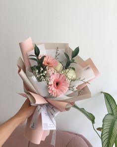 a person holding a bouquet of flowers on top of a couch next to a potted plant