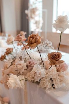 some flowers are sitting on a table with white linens and other things in the background