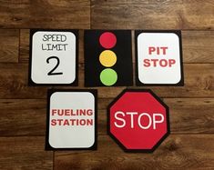 four different signs are displayed on a wooden floor, including one stop sign and the other two