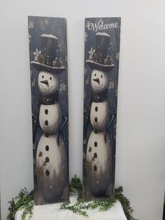 two snowmen standing next to each other in front of a sign that says welcome