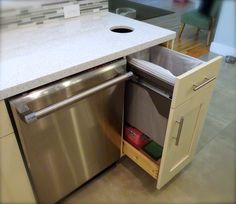 an open dishwasher in a kitchen next to a counter with a trash can