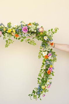 a person is holding a floral arrangement in their hand and the flowers are hanging down