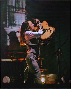 a woman holding an electric guitar on stage