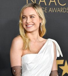 a woman in white dress and gloves smiling at the camera with her arm wrapped around her shoulder