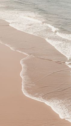 two people walking along the beach with surfboards