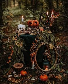 a table topped with pumpkins and candles in the woods