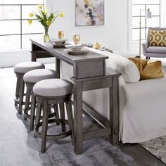 a kitchen table with stools next to it in front of a couch and chairs