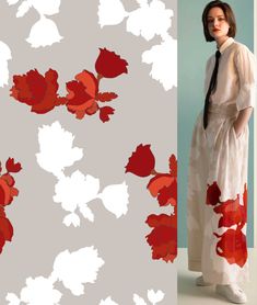 a woman standing in front of a wall with red flowers on it and a white background