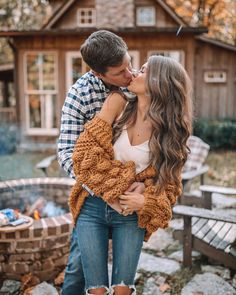 a man and woman kissing in front of a fire pit