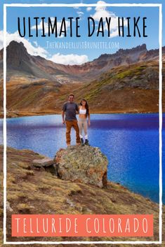 a man and woman standing on top of a rock next to a lake