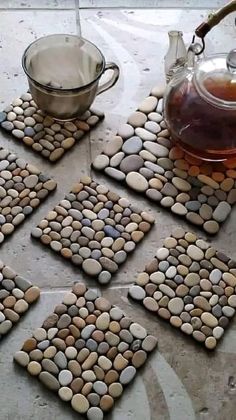 there are four coasters made out of rocks and tea pot on the table next to them