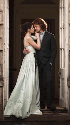 a man and woman standing in front of a doorway together, dressed in formal clothing