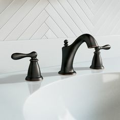 two black faucets sitting on top of a white sink