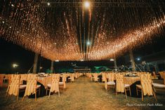 an outdoor venue with tables and chairs covered in lights