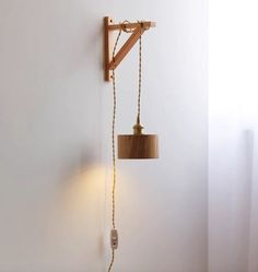 a wooden light fixture hanging from the side of a white wall next to a lamp