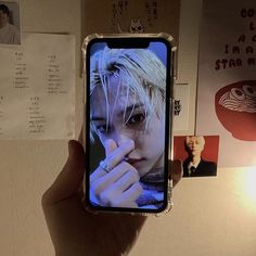 someone is holding up their cell phone with the image of an anime character on it