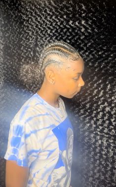 a woman with braids standing in front of a black and white wall, wearing a t - shirt