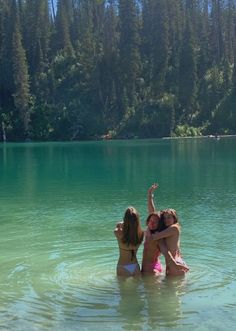 three girls are in the water with their arms around each other