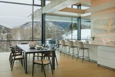 a dining room table and chairs in front of a large window overlooking the mountain range