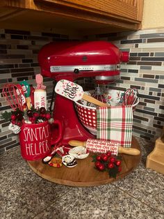 a red mixer sitting on top of a counter next to other kitchen accessories and decor