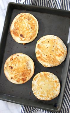 four flat breads on a baking sheet ready to go in the oven for cooking