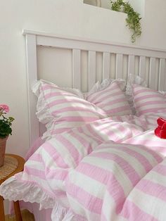 a bed with pink and white striped bedspread next to a potted plant