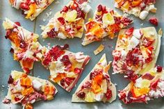 several pieces of fruit and cheese pizza on a baking sheet with other slices cut into squares