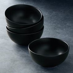 three black bowls are stacked on top of each other in front of a gray background