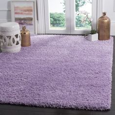 a purple rug in front of a window with two vases on the floor next to it