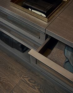 an open drawer on the side of a wooden cabinet with books and papers in it