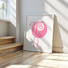 an image of a pink ball on the floor in front of a white framed poster